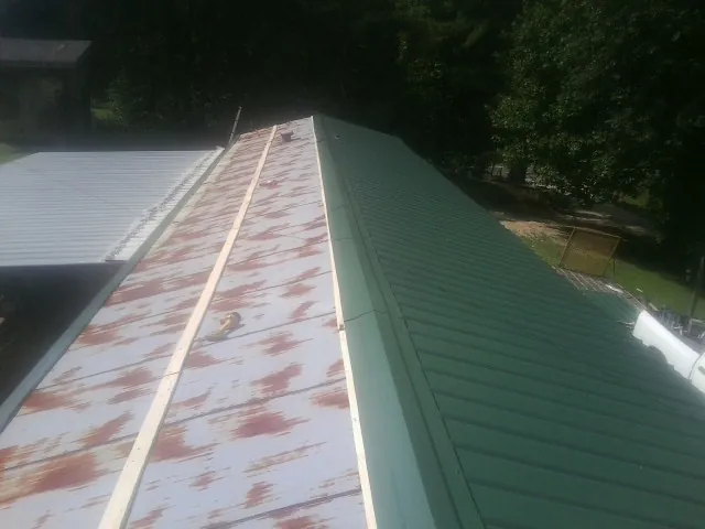 Old rusted panels beside newly installed green metal roofing — Wind Damage Roof Repair by Roofing Brothers in Carlstadt