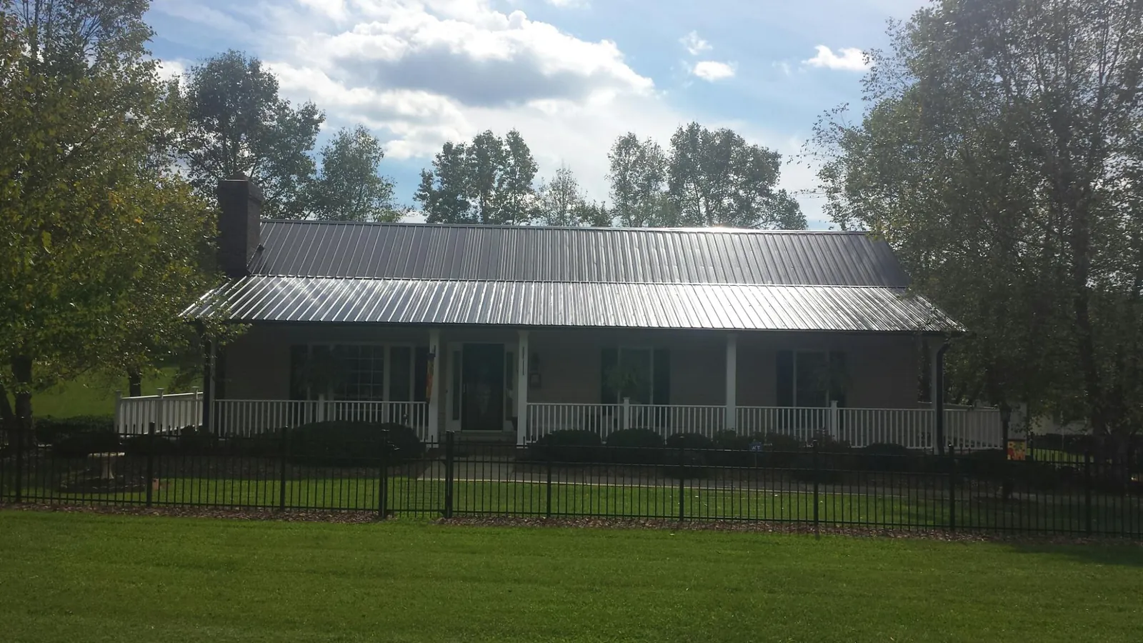 Gray metal roof on a brick ranch with a full width front porch — Gutter Guard Installation work by our crew in Carlstadt