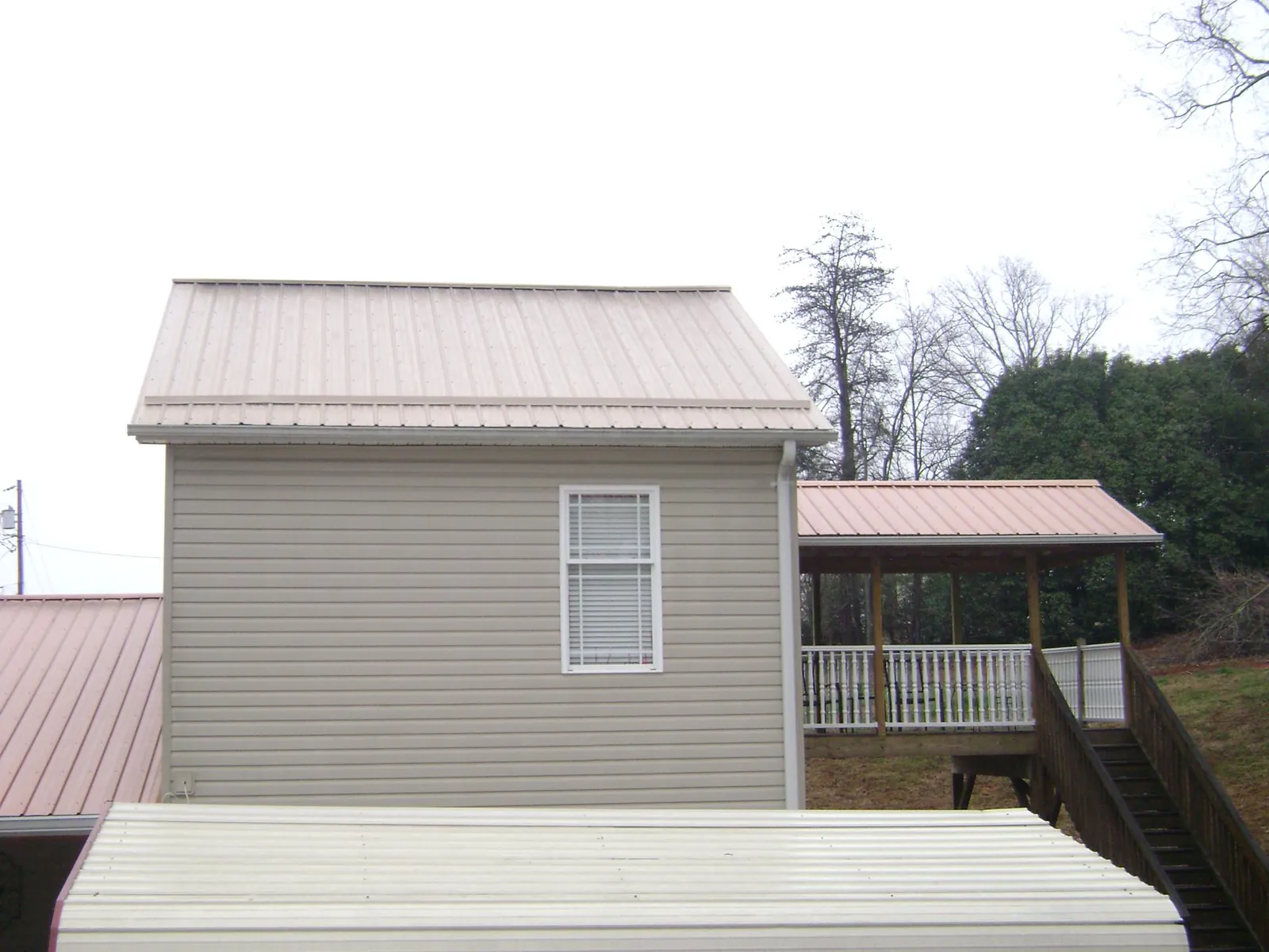 Tan metal roofs on a two story addition and attached porch, from a Roof Replacement job in Carlstadt