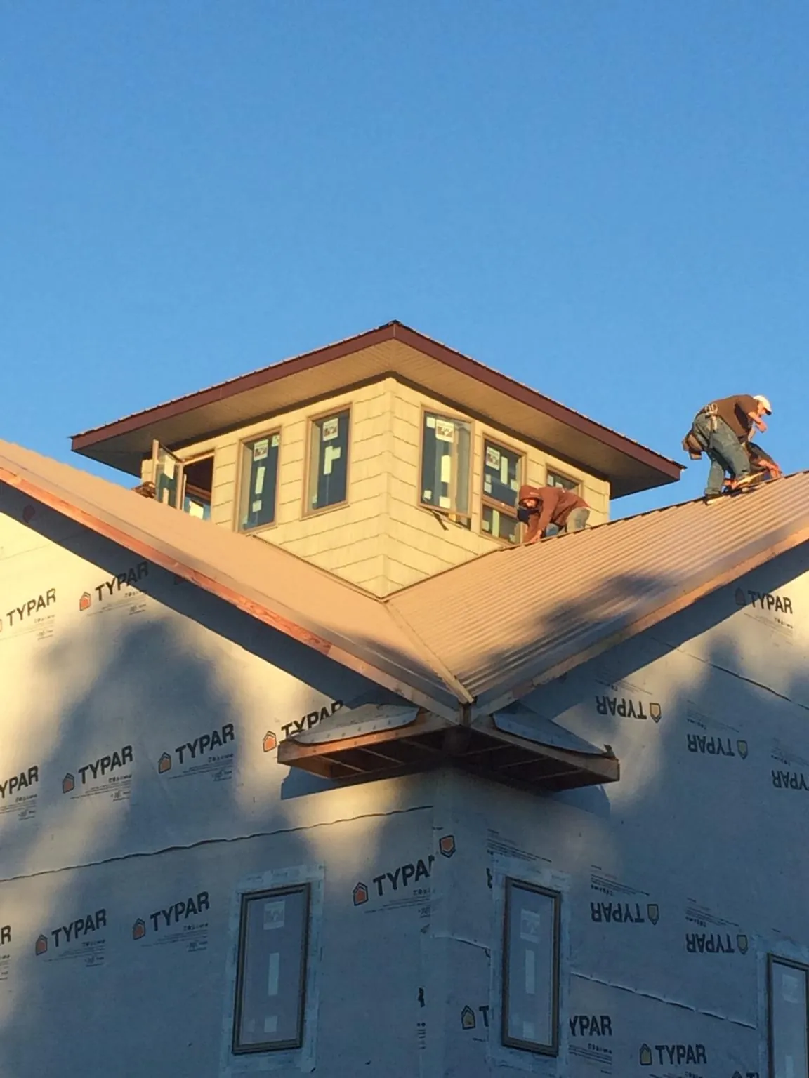 Roofers working around a rooftop cupola on a new metal roof at sunset — Roof Waterproofing in Carlstadt by Roofing Brothers